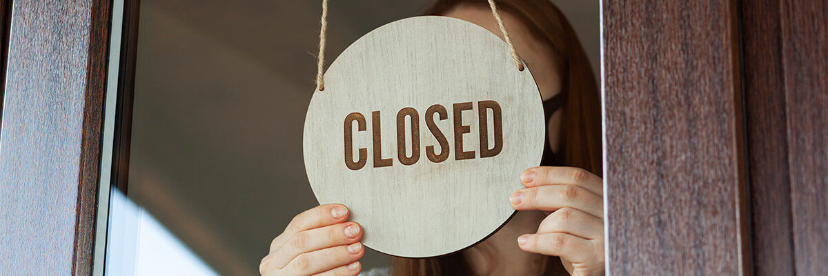 Woman switching sign to close in store window.